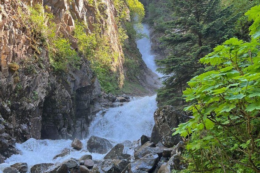 Une cascade se déversant dans un ravin rocheux, entourée d’une végétation luxuriante. 1