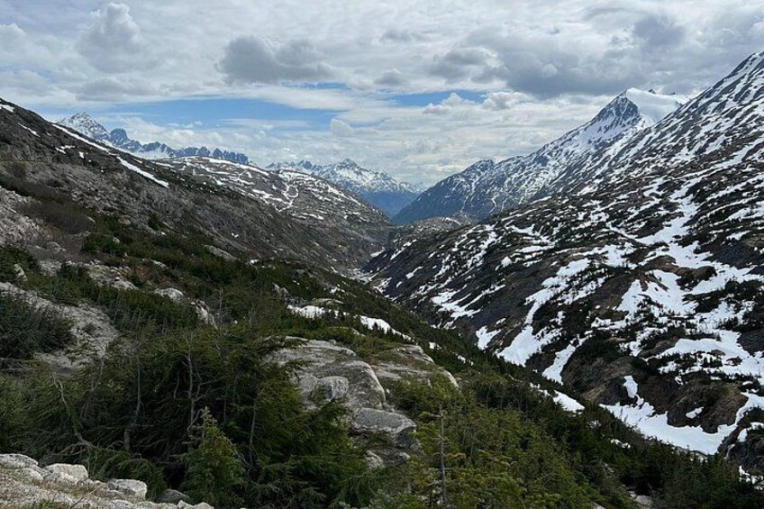 Un paysage montagneux caractérisé par des sommets enneigés, un terrain rocheux et une forêt dense. 3