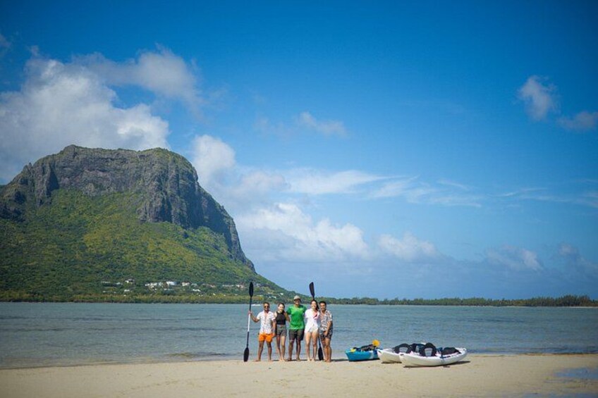A group of people on a beach with a mountain in the background. 2