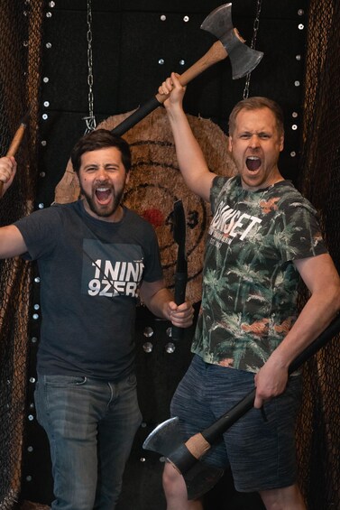 Two men holding axes in front of a cave-like backdrop. 5