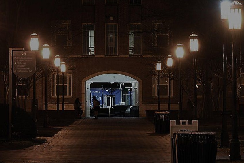 Escena nocturna con la entrada de un edificio, farolas y un cartel. 2