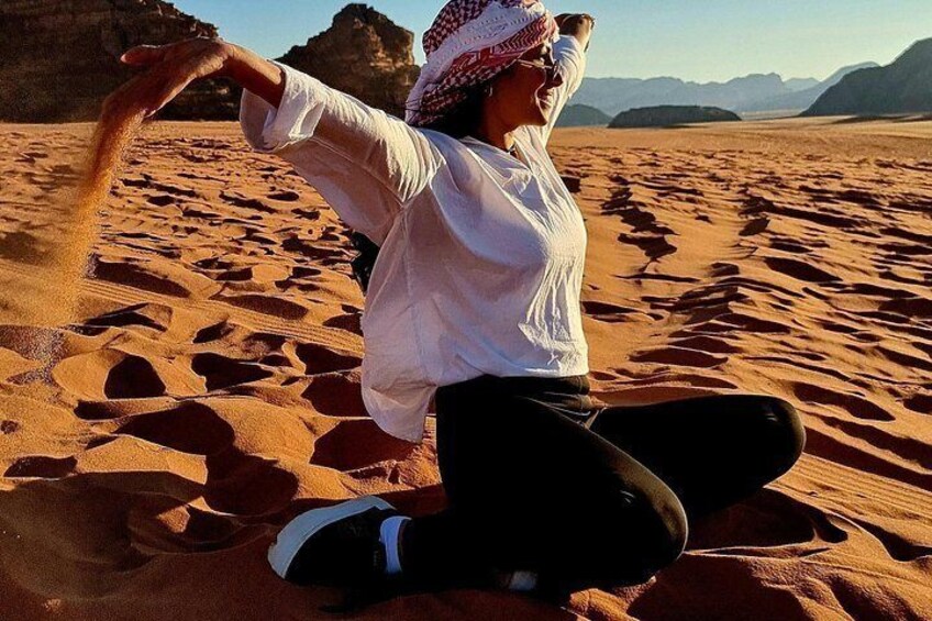 Una persona sentada sobre dunas de arena con un paisaje desértico al fondo. 2