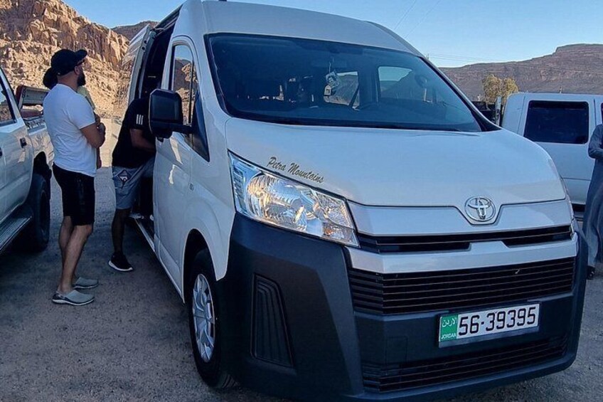 Una camioneta blanca Toyota con matrícula visible, estacionada en una zona desértica con terreno rocoso al fondo. 3