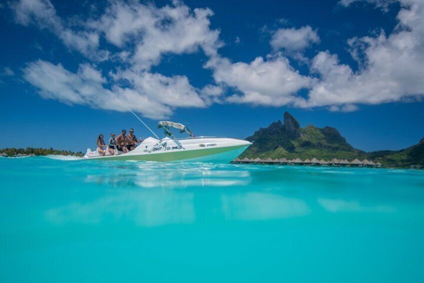 Un bateau blanc avec des personnes à bord, naviguant sur une mer turquoise, une montagne en arrière-plan et un ciel dégagé. 4