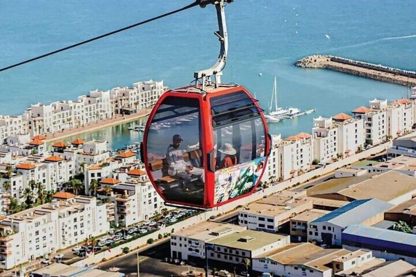 A cable car with passengers, a coastal cityscape, and a marina. 1
