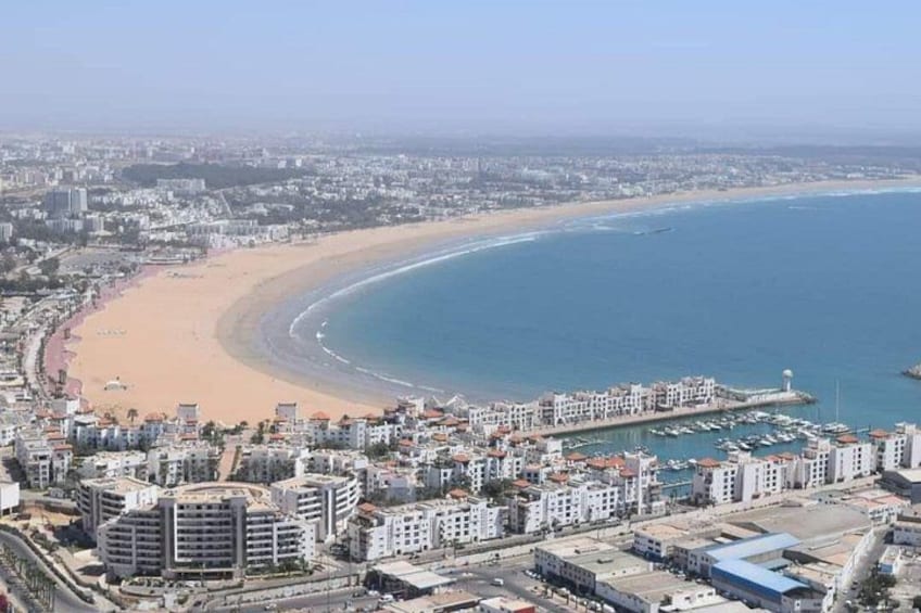 Un paysage urbain côtier avec une plage, des bâtiments et un port de plaisance. 2
