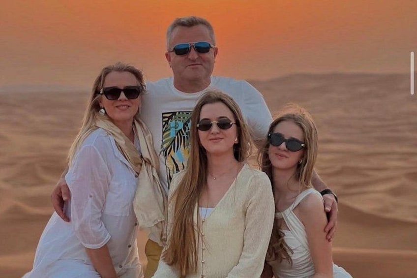 Una famiglia di quattro persone in un paesaggio desertico, con dune di sabbia sullo sfondo. 2