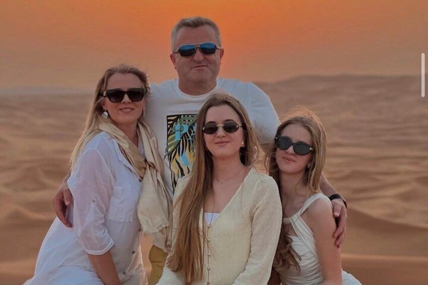 Una familia de cuatro personas en un paisaje desértico, con dunas de arena al fondo. 2