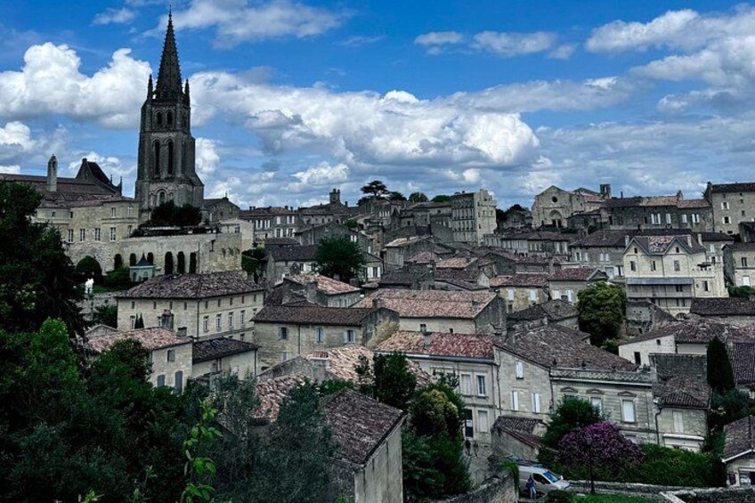 A historic town with a prominent church tower, dense residential buildings, and lush greenery. 4