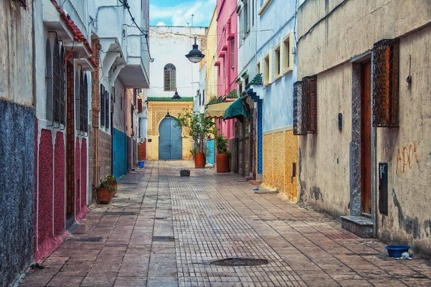Tranquil scene of a winding street in the Medina of Rabat, showcasing traditional Moroccan architecture with whitewashed walls and colorful accents. 3