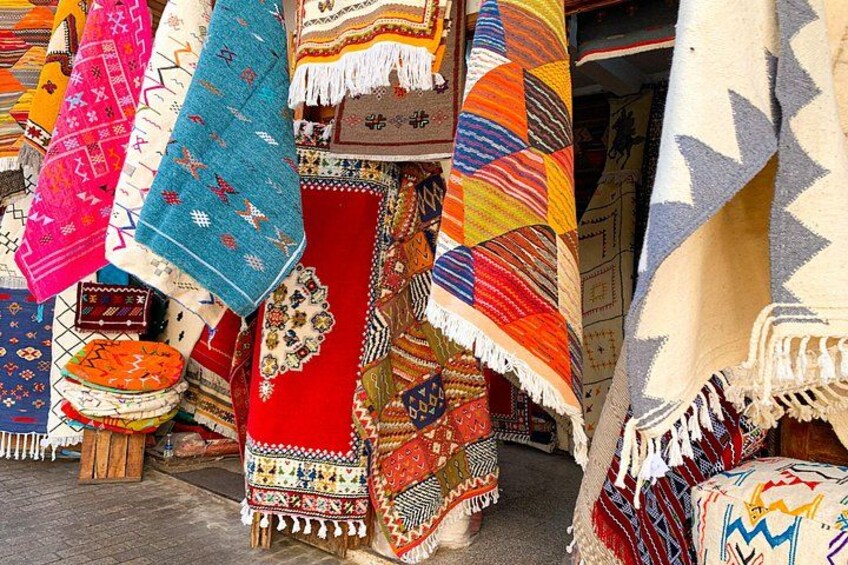 Vibrant display of handmade Moroccan rugs in a shop within the Medina, showcasing intricate patterns and bold colors that reflect the country's rich craft traditions. 5
