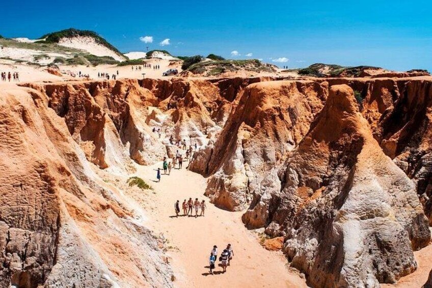 A canyon with a dirt path and people walking. 4