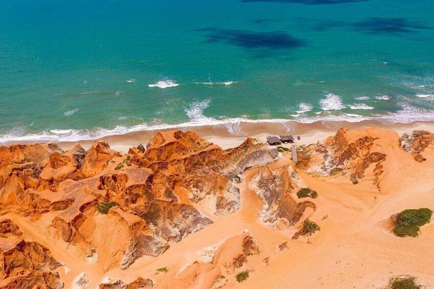 A coastal landscape with rocky formations and a sandy beach. 5