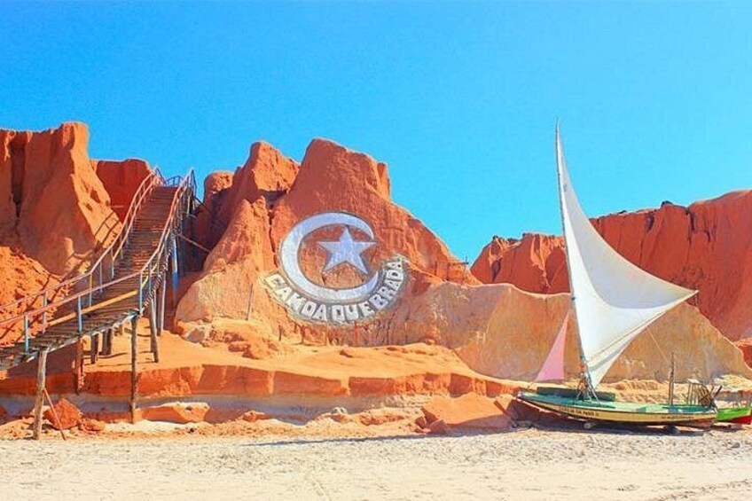 A desert landscape with a large rock formation, a sailboat, and a staircase leading up to a structure with a star emblem. 1