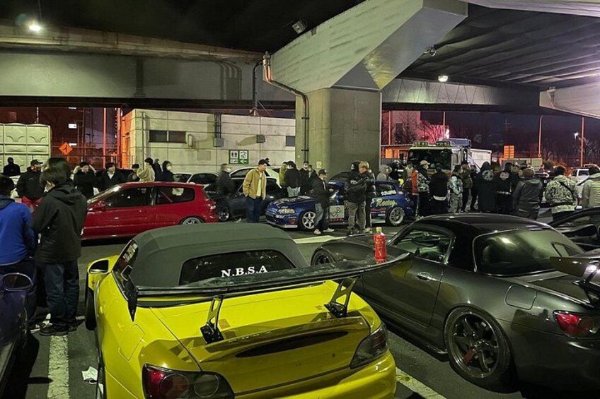 Un parcheggio affollato con diverse auto e persone. 4