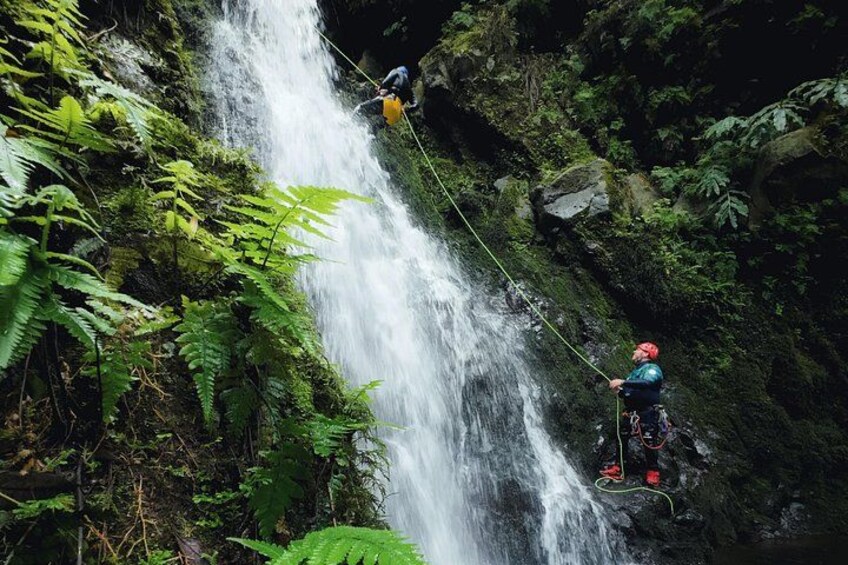 A waterfall with two people rappelling down. 4