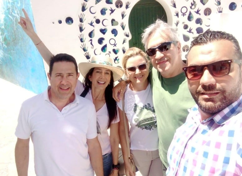 A group of people posing in front of a building with a unique wall design. 5