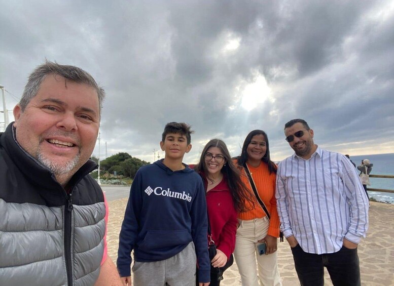 A group of people standing on a beach with a cloudy sky. 4