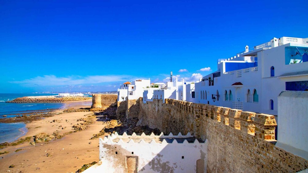 A coastal town with white buildings, a stone wall, and a beach. 2
