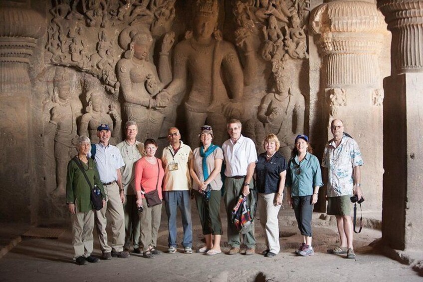 Un groupe de personnes se tient devant une sculpture en pierre ornée de motifs complexes. 1