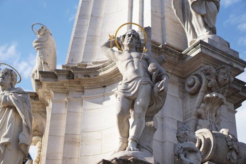 Une statue classique, surmontée d’une auréole, qui repose sur un piédestal orné de sculptures complexes. 3