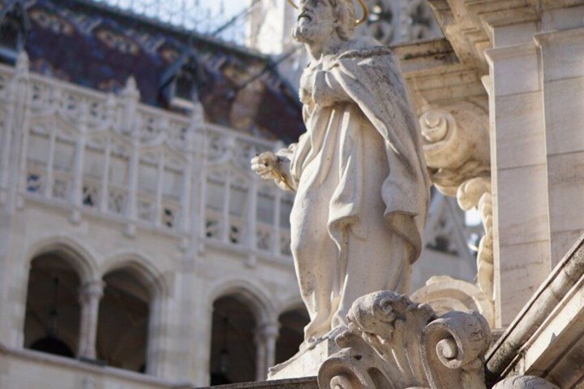 Une statue classique, placée au coin d’un bâtiment, avec des détails architecturaux élaborés et des fenêtres en arc de cercle en arrière-plan. 4