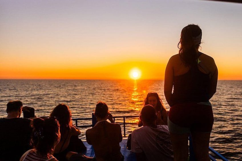 Un atardecer sobre el océano con gente en un barco. 3
