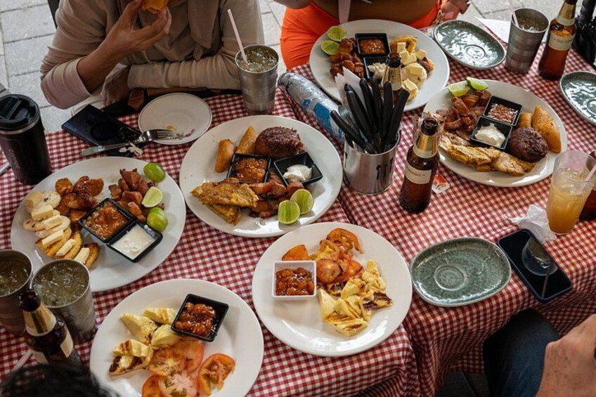 A group of people dining at an outdoor table with various dishes and drinks. 5
