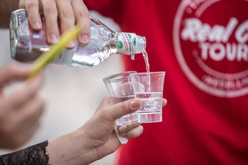 A person pouring a clear liquid from a bottle into a glass. 4