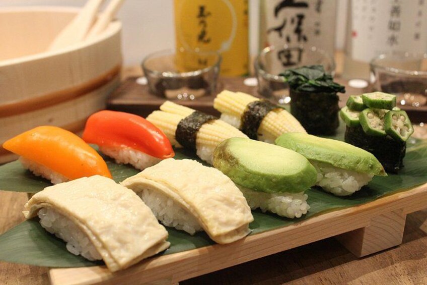 A wooden tray with various sushi pieces, including rolls and nigiri, on a green leaf. 2