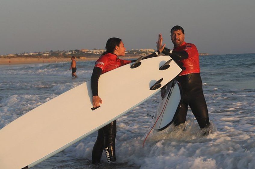 Twee mensen in neopreenpakken met surfplanken op het strand. 4