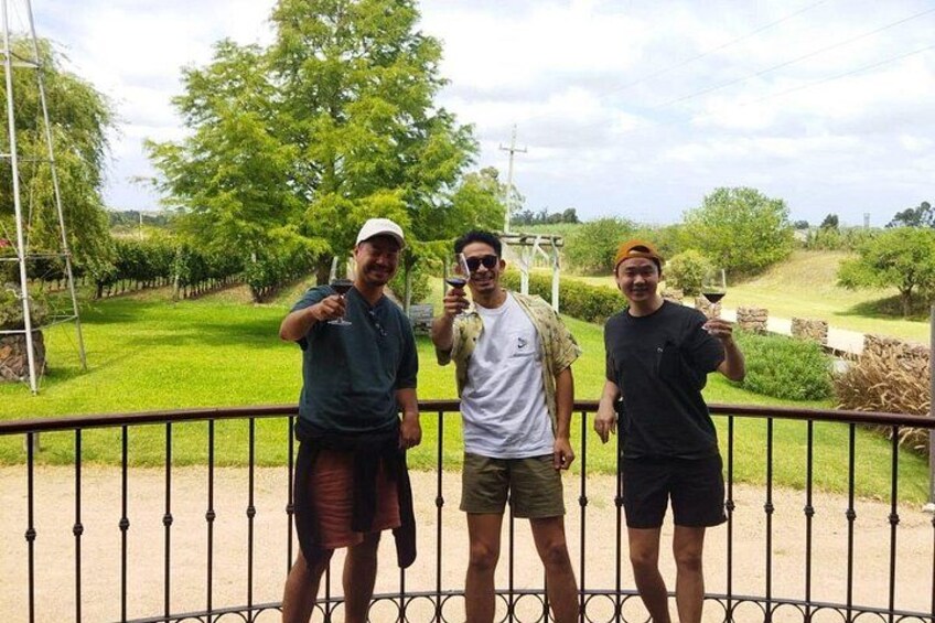 Three people standing by a fence with a vineyard in the background. 5