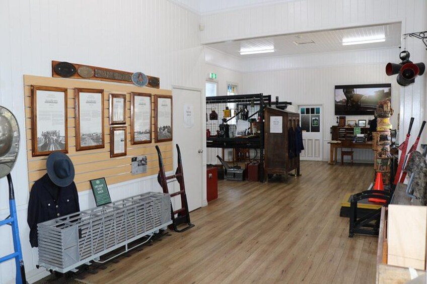 A room with wooden floors, a wall with framed documents, and various items on shelves. 4