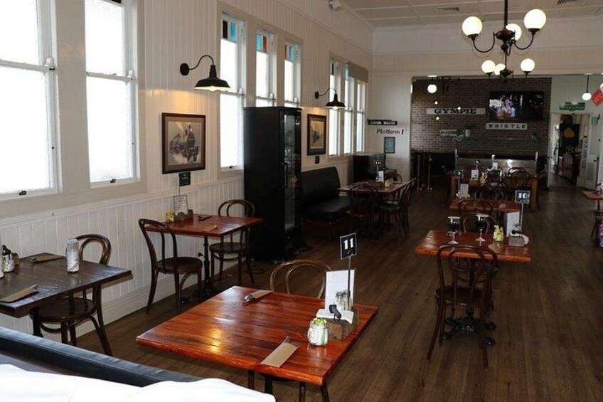 A restaurant interior with wooden tables and chairs, a counter, and a bar area. 2