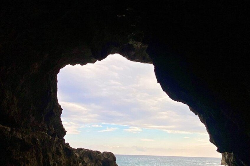A cave entrance with a view of the ocean and sky. 5