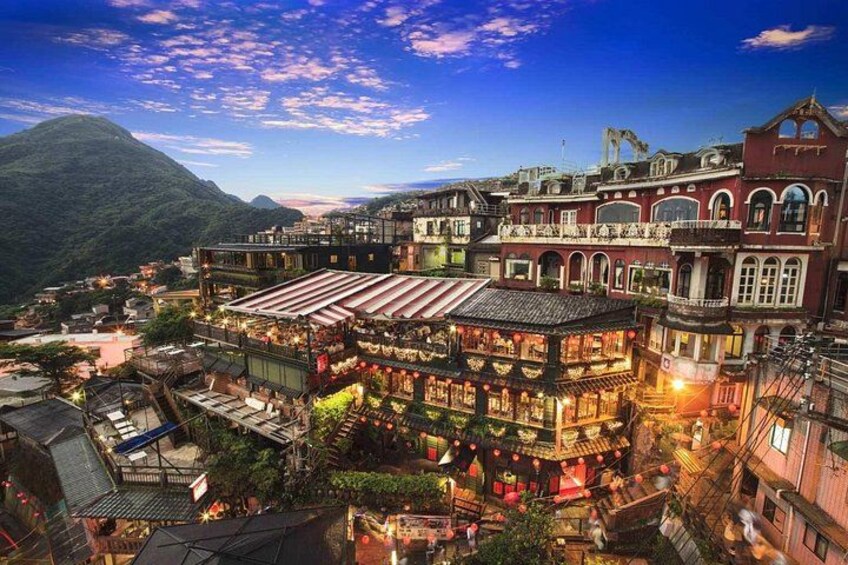 Un pueblo tradicional con edificios de varios pisos, un río y una montaña al fondo. 1