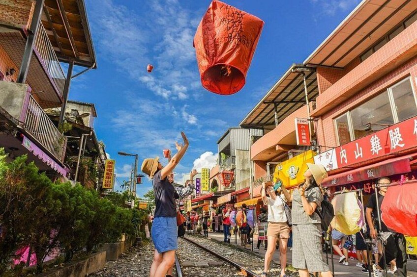 Una calle con gente soltando linternas rojas al cielo. 2
