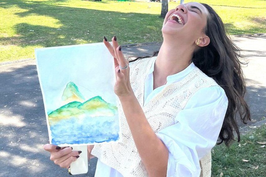 Una persona sosteniendo una pintura a técnica mixta de un paisaje montañoso. 1