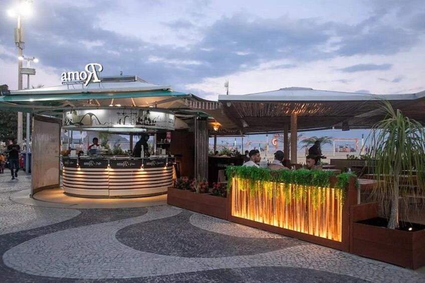 Un restaurante al aire libre con un diseño moderno, que cuenta con un mostrador curvo y una cubierta. 2