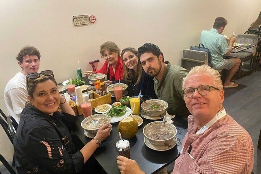 A group of people sitting around a table with various dishes and drinks. 5