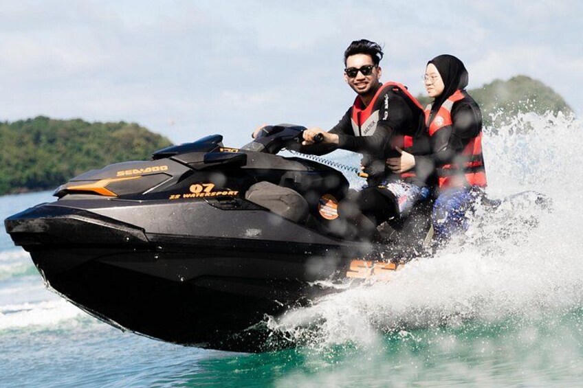 Una persona guida un jet ski nero Sea-Doo 07 su un'acqua calma, con un paesaggio verde sullo sfondo. 3