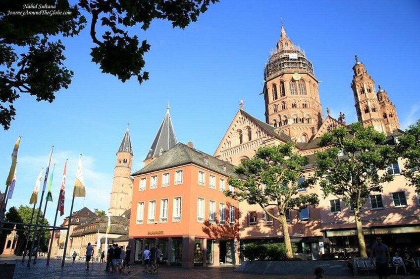 Un bâtiment historique doté d’une tour horloge, avec un bâtiment rouge en premier plan. 2