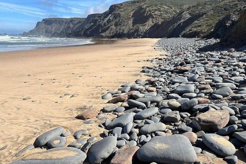 Une plage rocheuse, parsemée de gros blocs de pierre et bordée d’une étendue de sable. 2