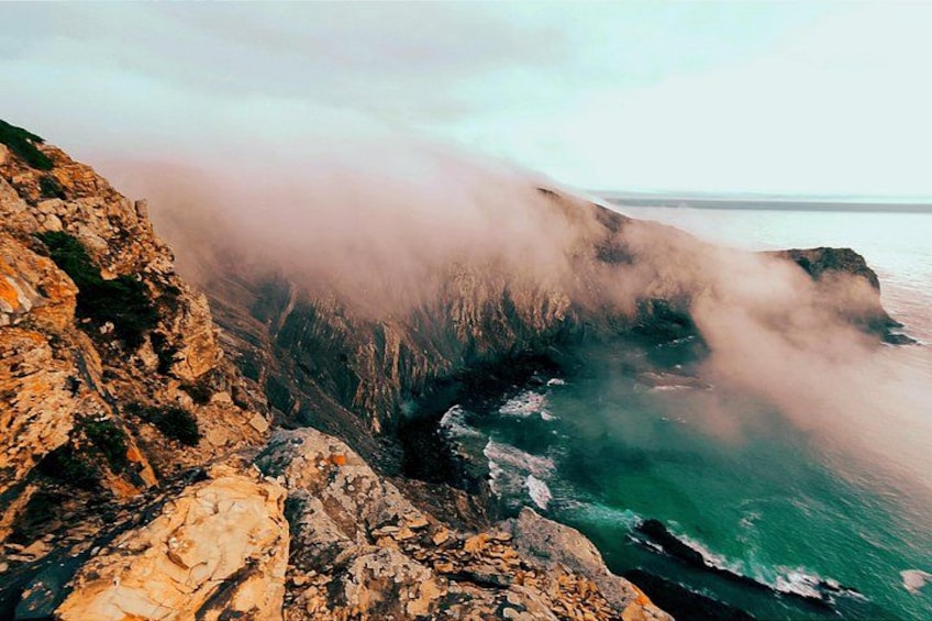 Une falaise côtière, et des nuages de brume s'élevant de l'océan. 1