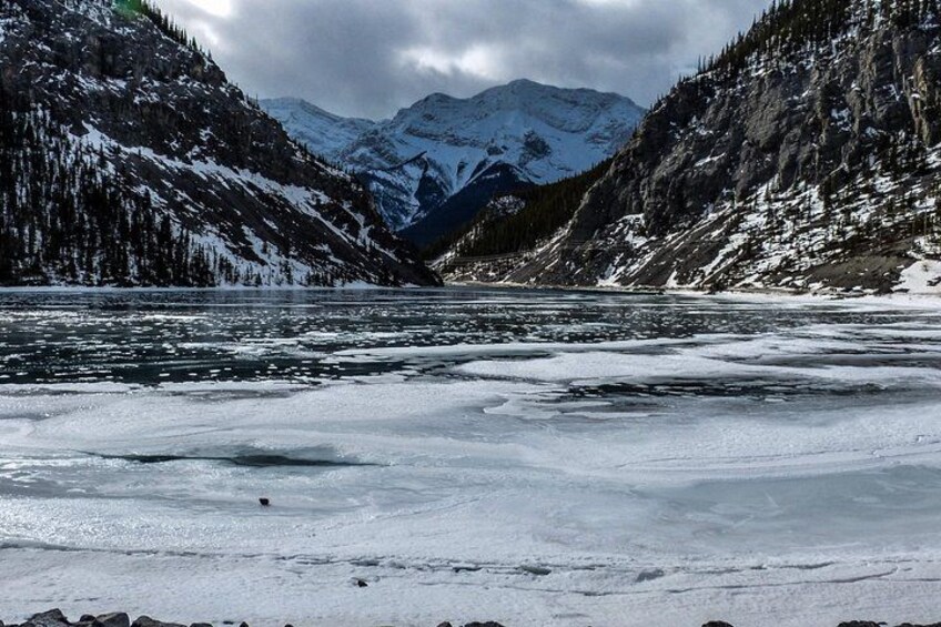 Un río congelado rodeado de montañas nevadas y bosques densos. 5