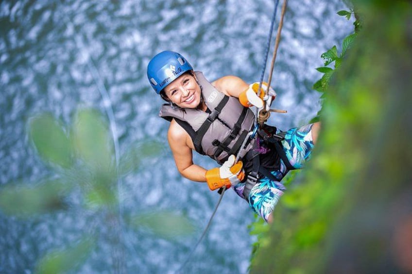A person zip-lining through a forested area with a river in the background. 1