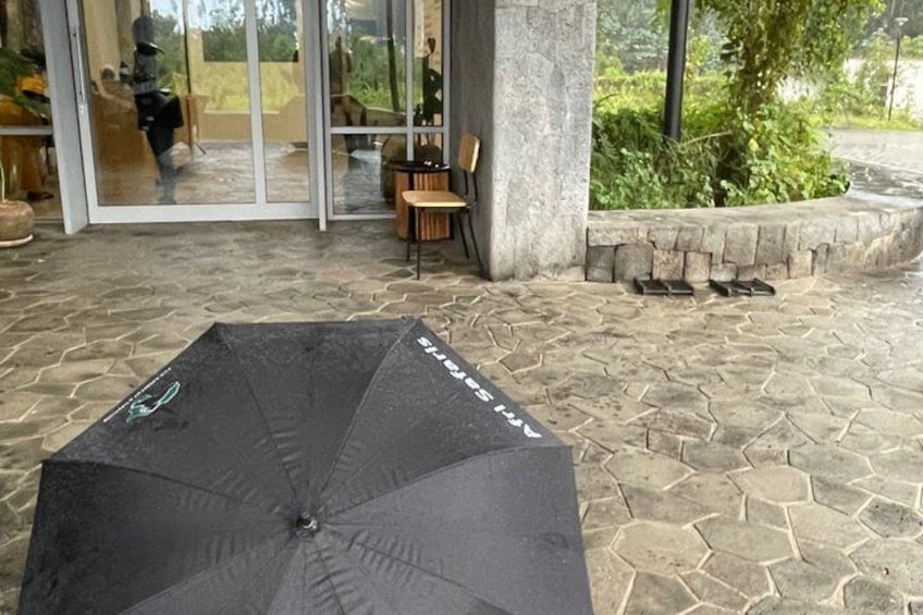 Un paraguas negro sobre un patio de piedra con un acceso por puerta de cristal y mobiliario exterior. 5