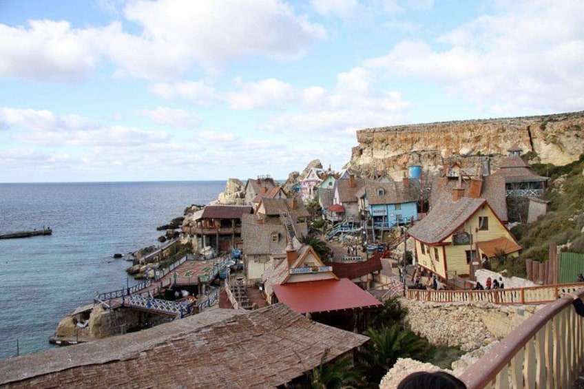 Un borgo costiero con edifici colorati, una scogliera rocciosa e un mare calmo. 1