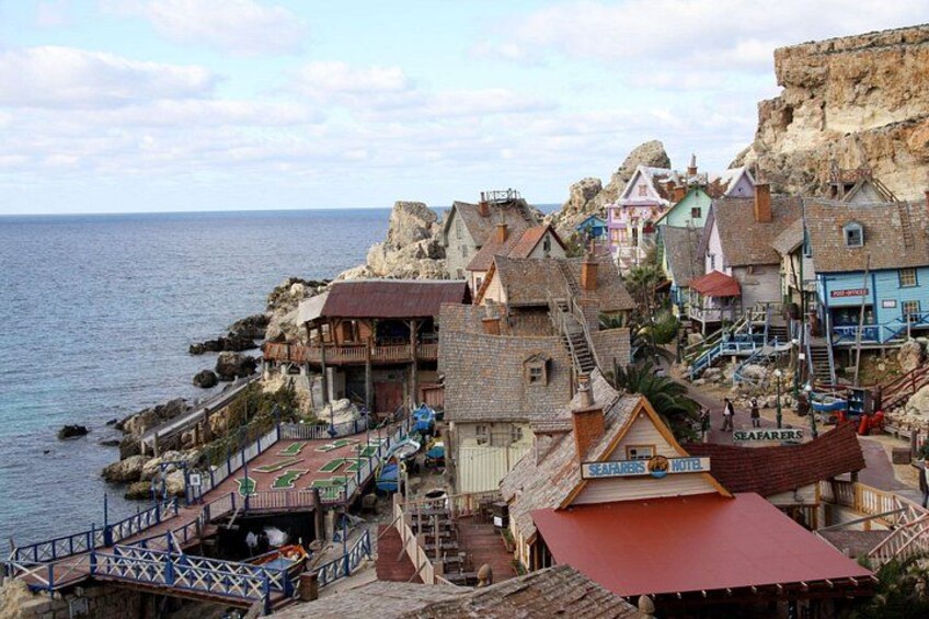 A coastal village with colorful buildings, a rocky cliff, and a beach. 1