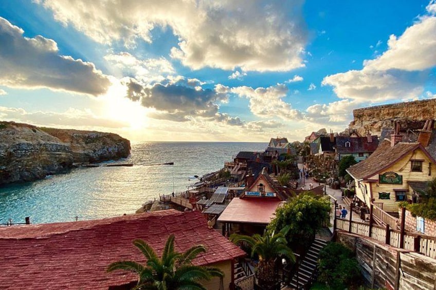 Un villaggio costiero con edifici, una costruzione con tetto rosso e una scogliera che si affaccia sul mare. 2